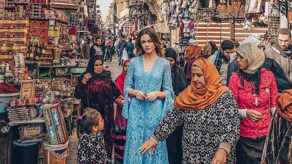 Woman in gown poses in busy Khan el-Khalili Market in Cairo, Egypt