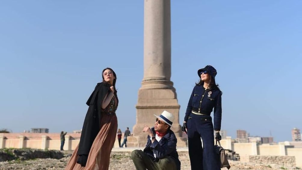 A man and two women pose in front of obelisk in Egypt
