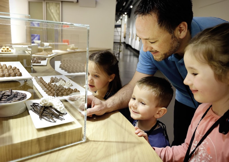 Father and children admiring the beautiful chocolates at a chocolate factory in Switzerland