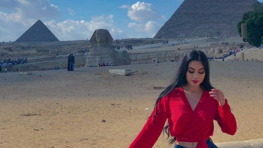 Girl poses with sphinx and pyramids in the background