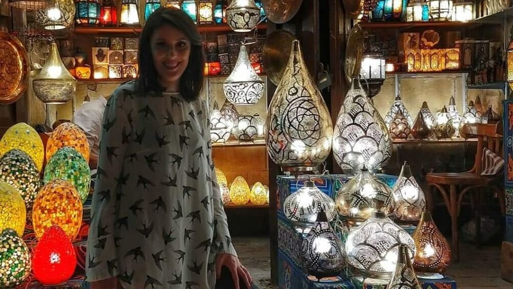 Woman poses with colorful metal lanterns at market in Egypt