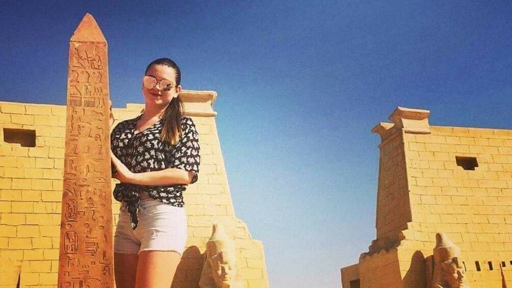 Woman poses near obelisk with hieroglyphics in Egypt