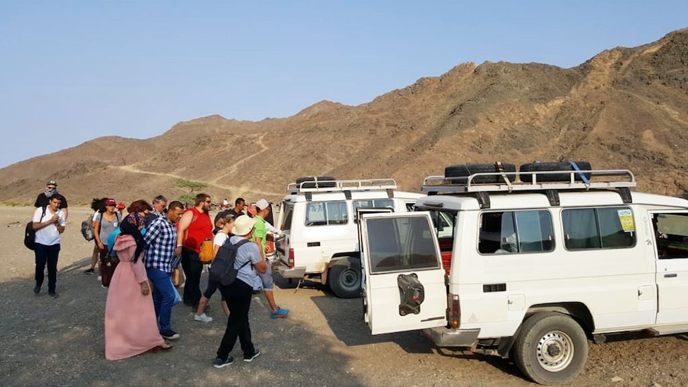 Large groups load into white jeeps in the Hurghada desert