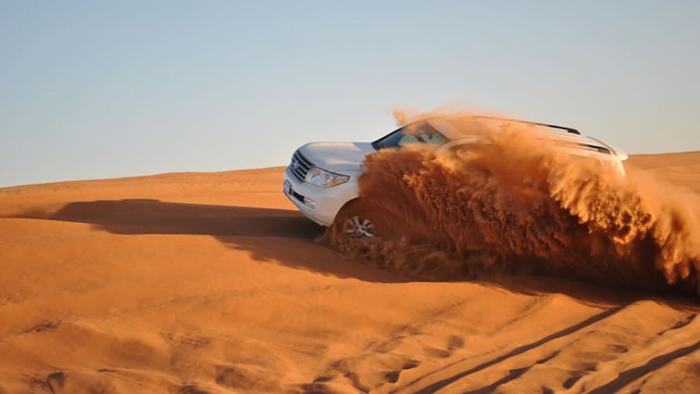 Jeep drives through Hurghada Desert kicking up orange sand