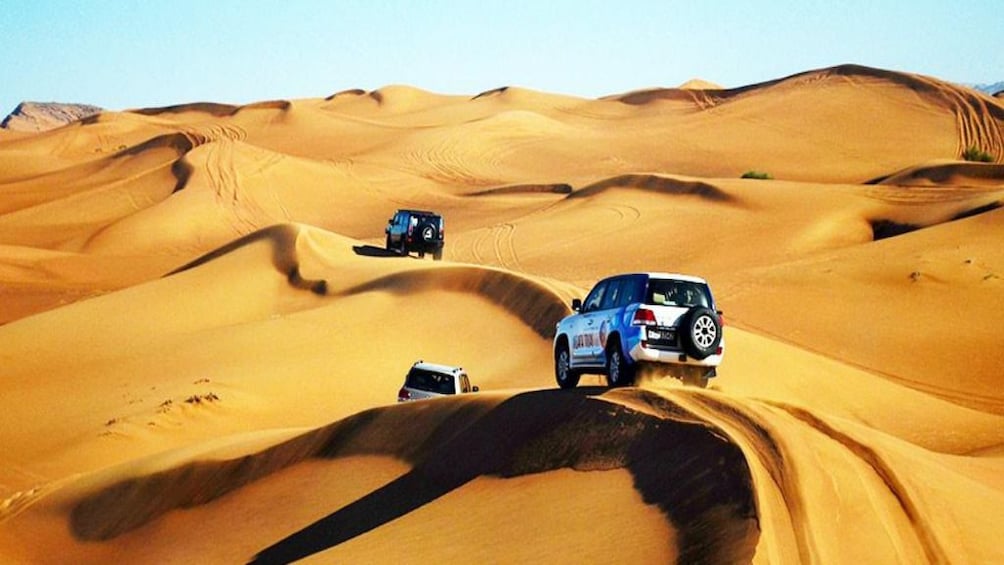 Panoramic view of three jeeps driving along path in Hurghada Desert