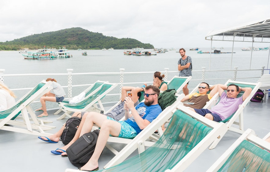 Tourists relax in lawn chairs on boat deck in Vietnam