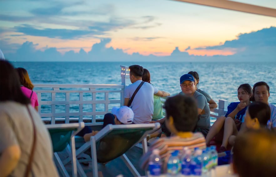 Group of tourists sit on deck in Vietnam at sunset 