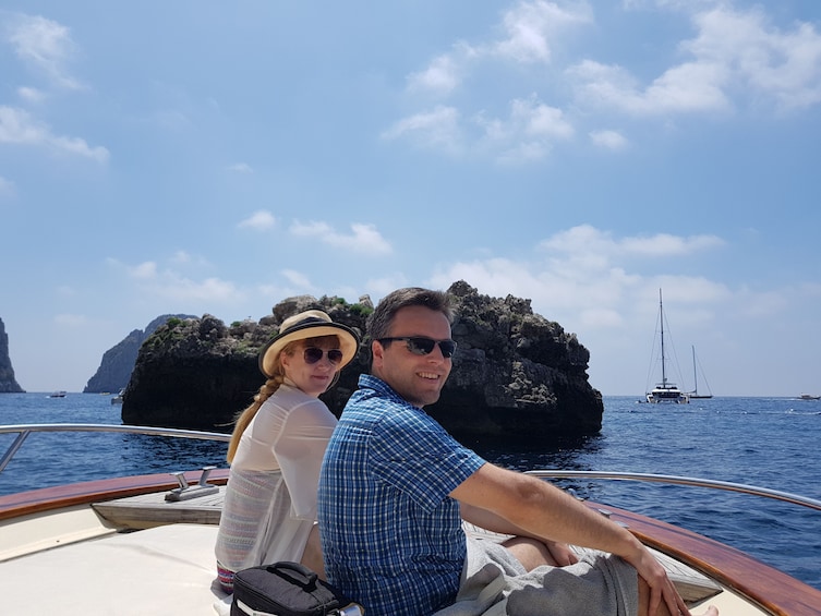 Show item 5 of 10. Man and woman sit on deck of small boat near Capri, Italy