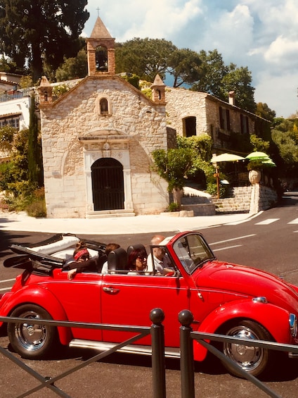 Small group in a VW Bug ride past an old chapel in Provence