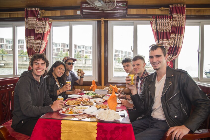 Tourists pose at a table full of food on cruise ship on Halong Bay