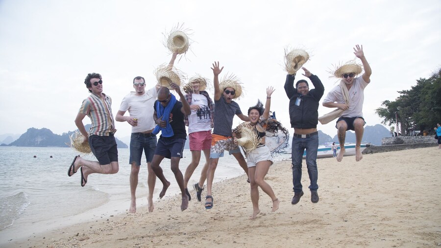 Tourists jump for a photo on a beach on Halong Bay