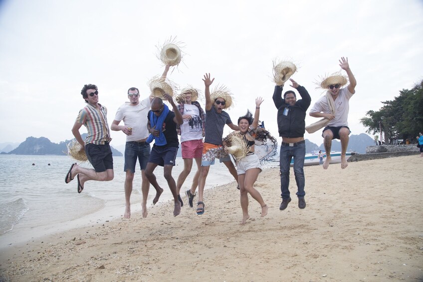 Tourists jump for a photo on a beach on Halong Bay