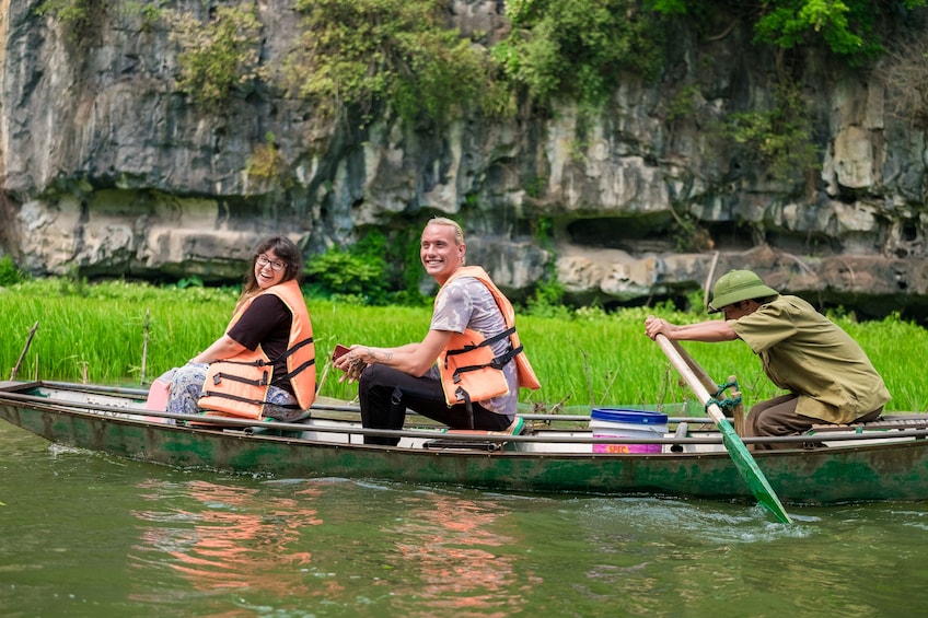 Tourists and guide in row boat in Tam Coc Wharf in Vietnam
