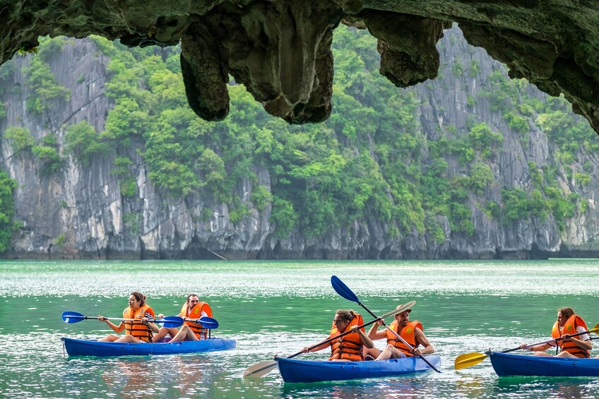 Tourists kayak under rock overhang in Halong Bay