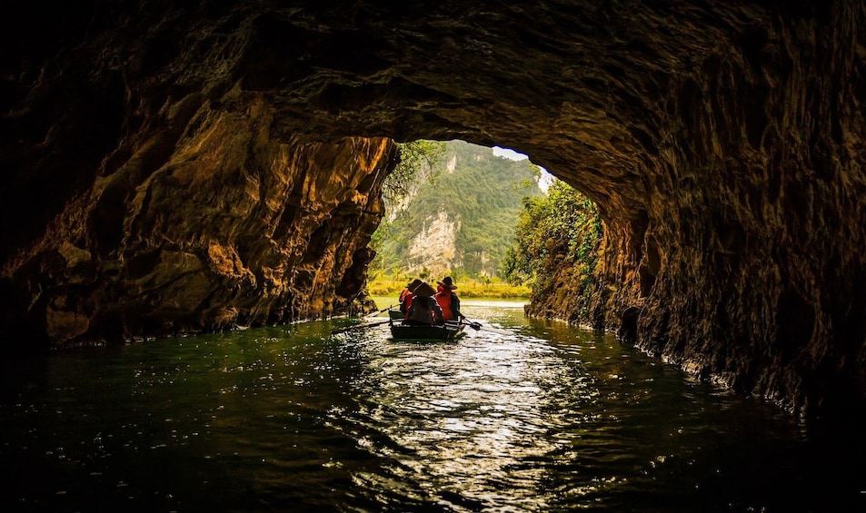 Small boat approaches opening of Mua Cave in Ninh Binh, Vietnam