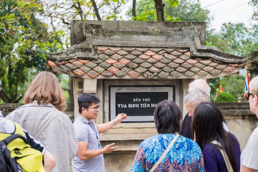 Tour guide shows tourists plaque for Vietnamese emperor Vua Dinh Tien Hoang 