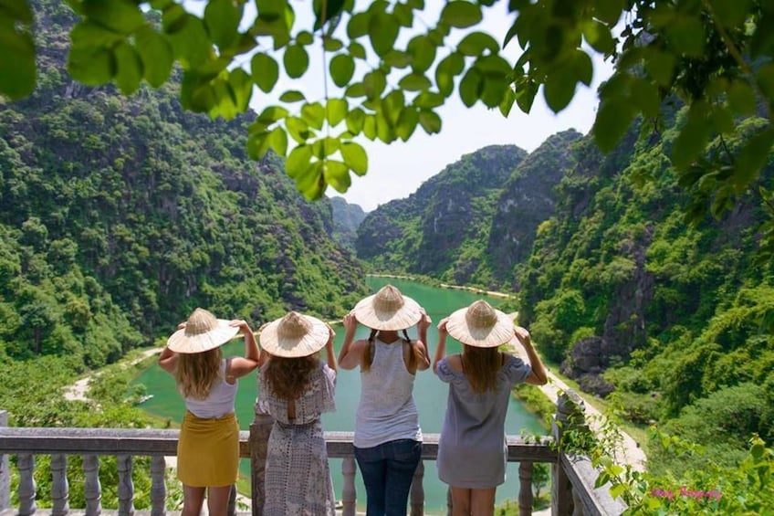 Women with large hats look out over Tam Coc Wharf
