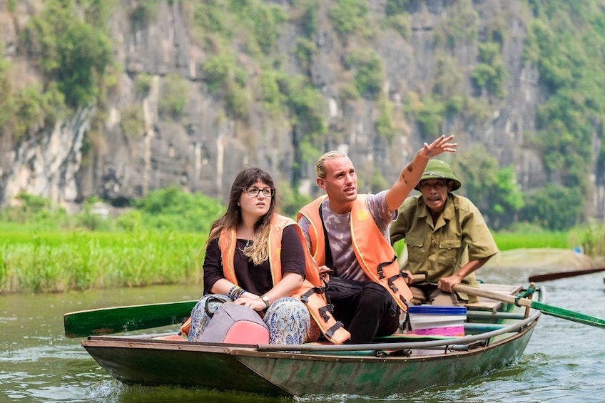 Tourists and tour guide on small rowboat in Tam Coc Wharf