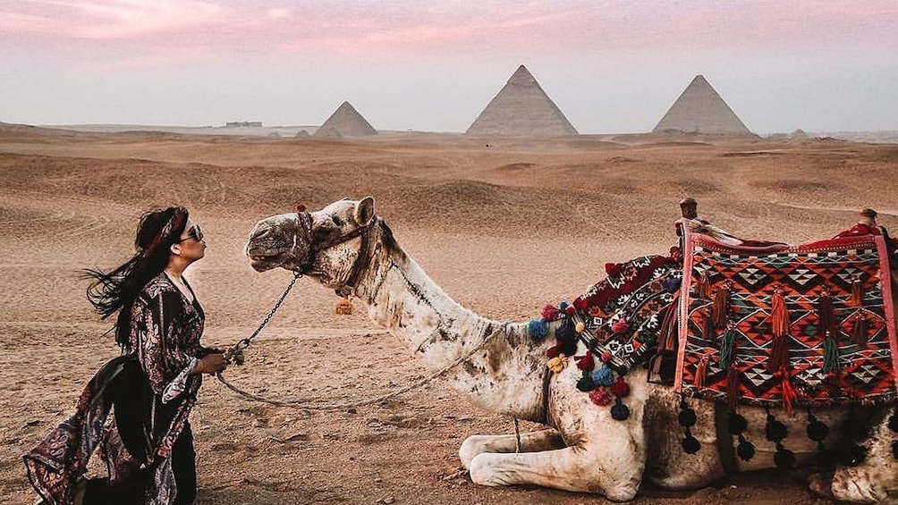 Woman and camel with the Pyramids of Giza in the background