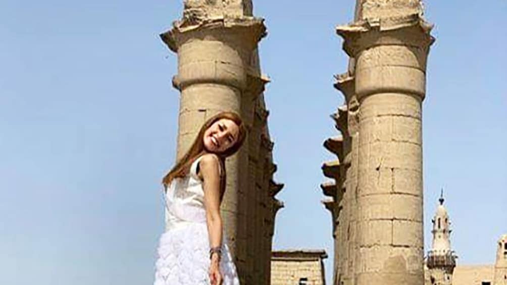 Woman in dress poses in front of columns of Luxor Temple