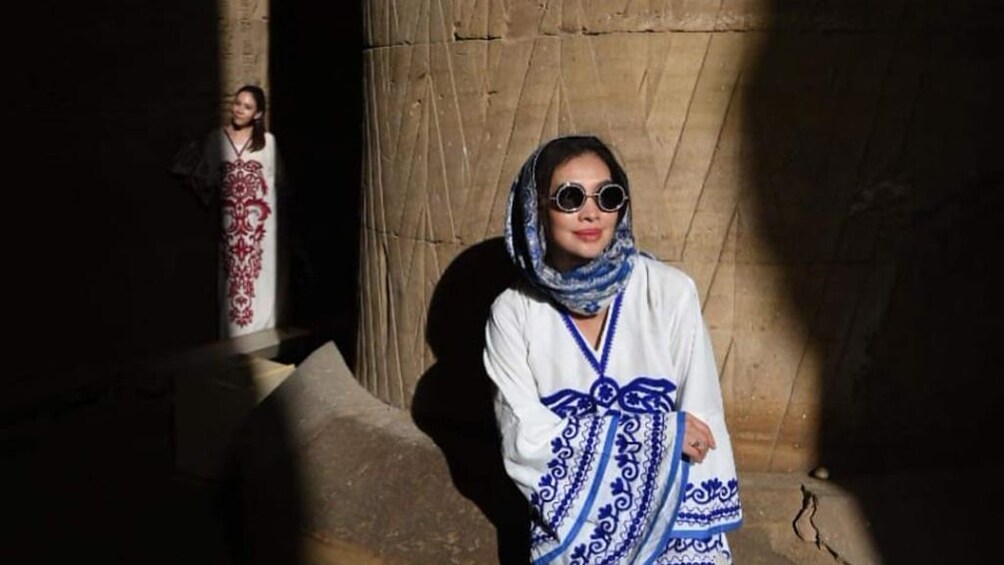 Woman with headscarf poses against a large pillar