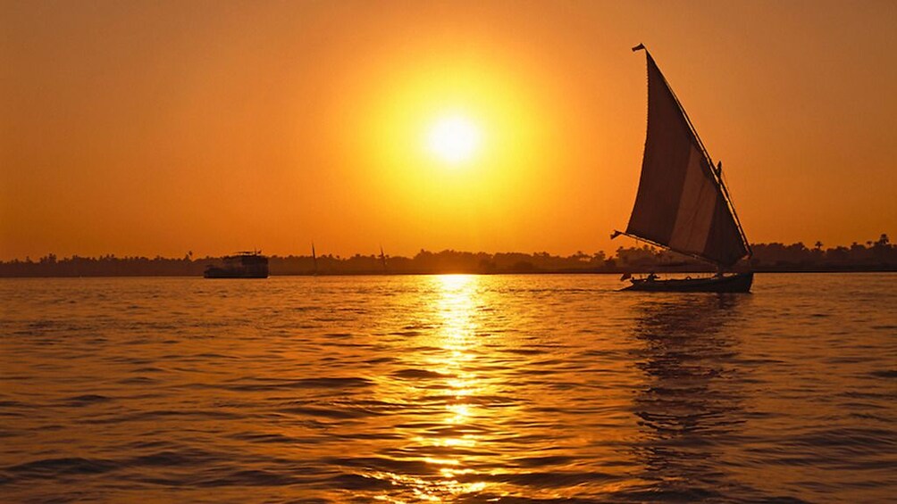 Sailboat on the Nile during bright, orange sunset