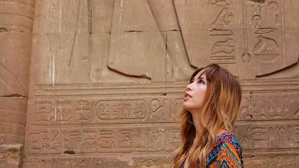 Closeup of woman posing in front of carved wall at the Temple of Horus at Edfu