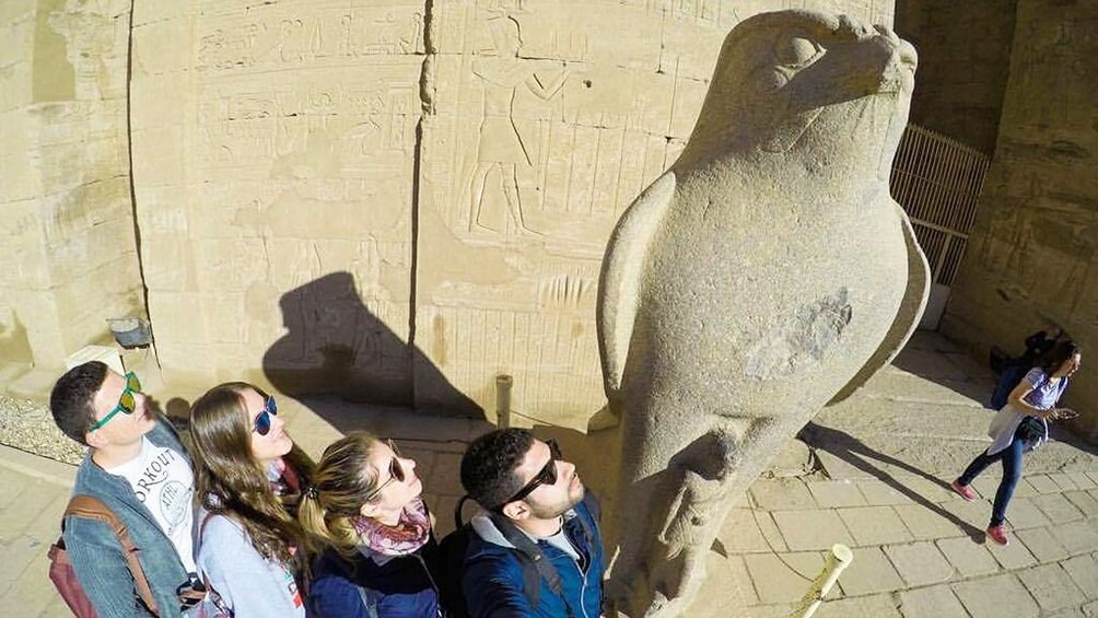 Four tourists look up at statue of Horus at the Temple of Horus at Edfu