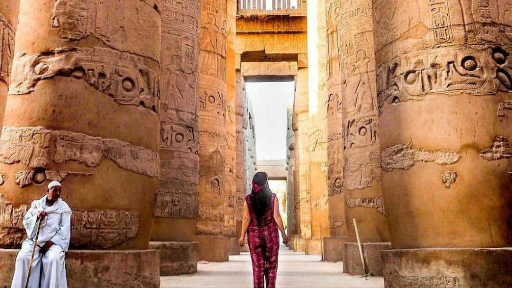 Woman walks among large Egyptian carved columns