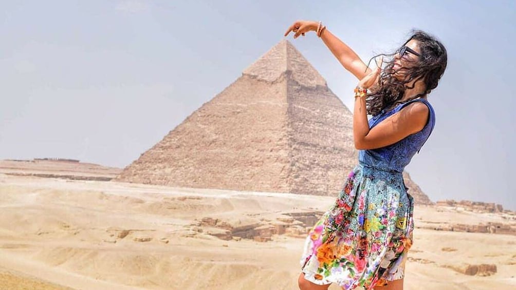 Woman pretends to touch the top of the Great Pyramid of Giza