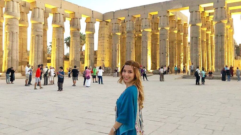 Woman poses on plaza in front of ancient Egyptian columns