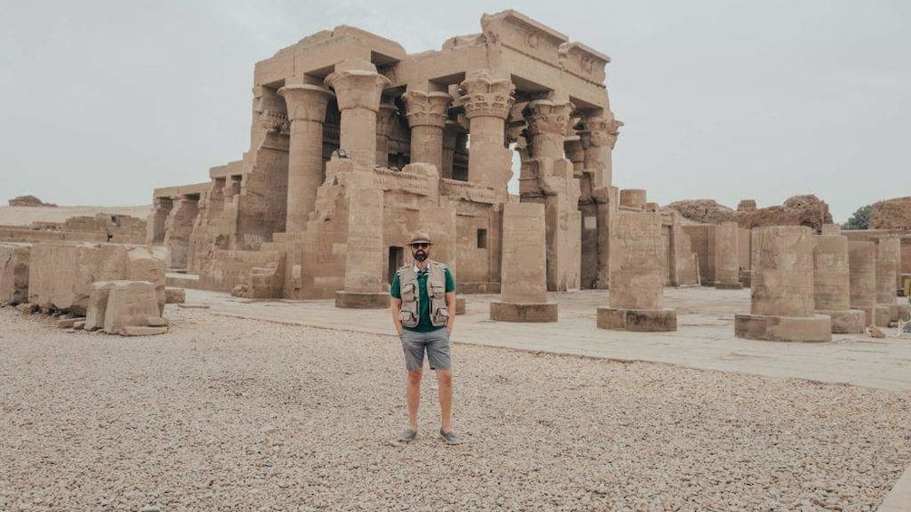 Man poses in front of Temple of Kom Ombo on a grey day