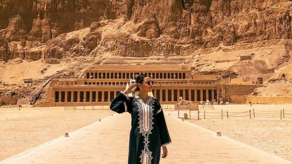 Woman poses in front of Mortuary Temple of Hatshepsut in Egypt
