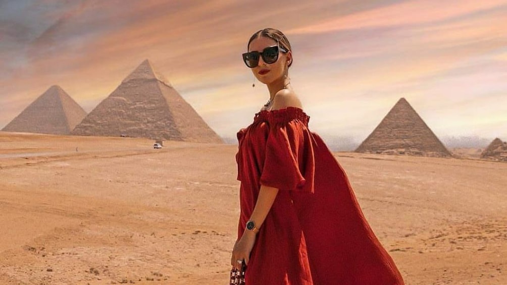 Woman in dress poses with Pyramids of Giza in the background