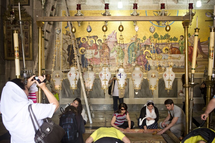 People gather around Stone of Anointing in the Church of the Holy Sepulchre