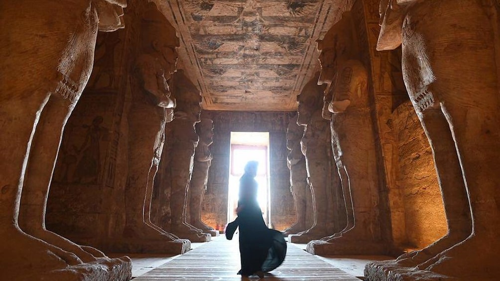 Man stands in temple with large sphynx statues