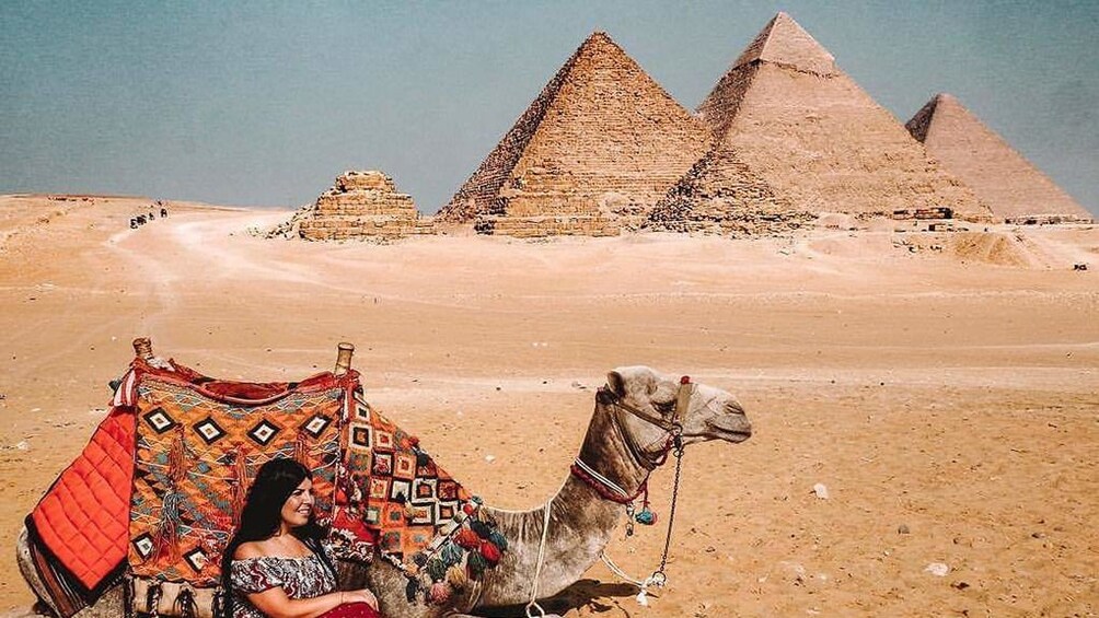 Woman and camel in front of the Pyramids of Giza