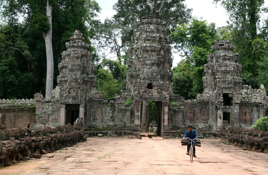 Man bicycles in front of Preah Khan gate