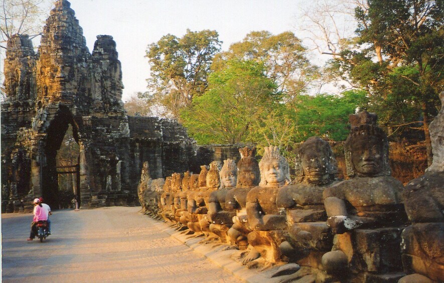 Lines of statues with temple in the background in Roluos, Cambodia