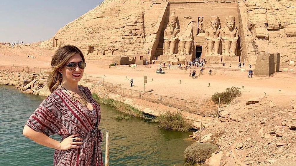 Woman poses in front of water and Abu Simbel Temples in Aswan, Egypt 