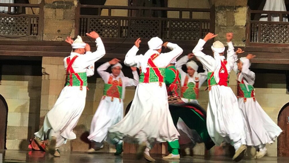 Circle of men in white, red and green perform a folk dance in Egypt