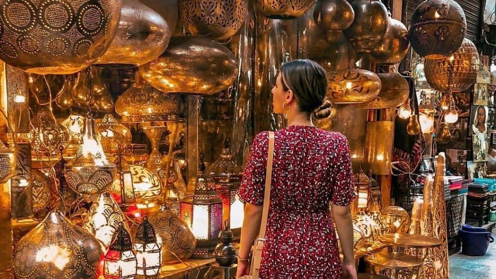 Woman looks around at gold, metal lanterns at El Khan Khalili market in Cairo, Egypt