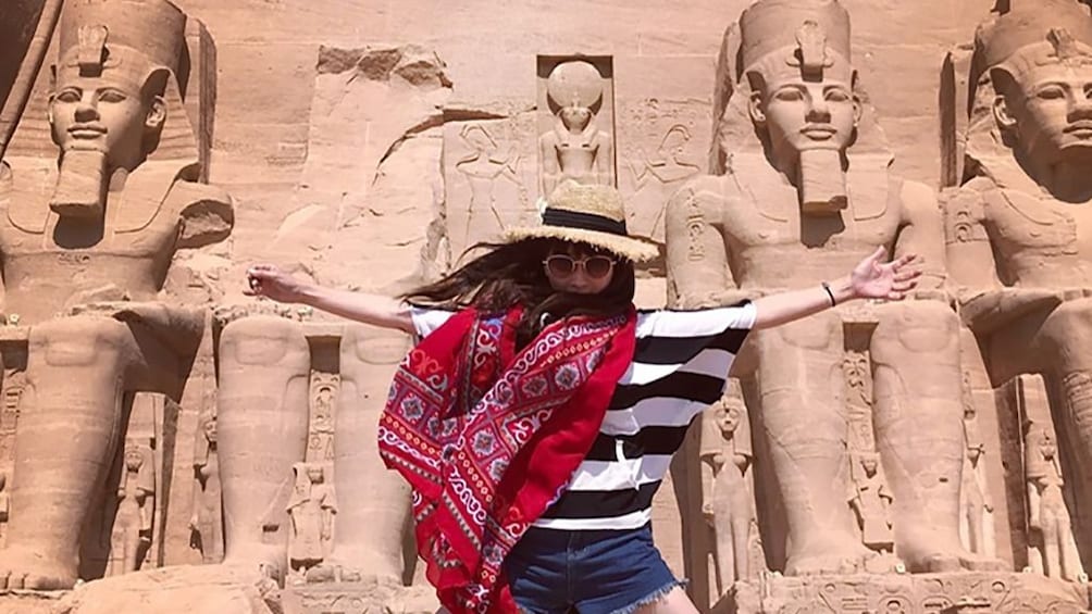 Woman poses with arms out to her side in front of Abu Simbel Temples