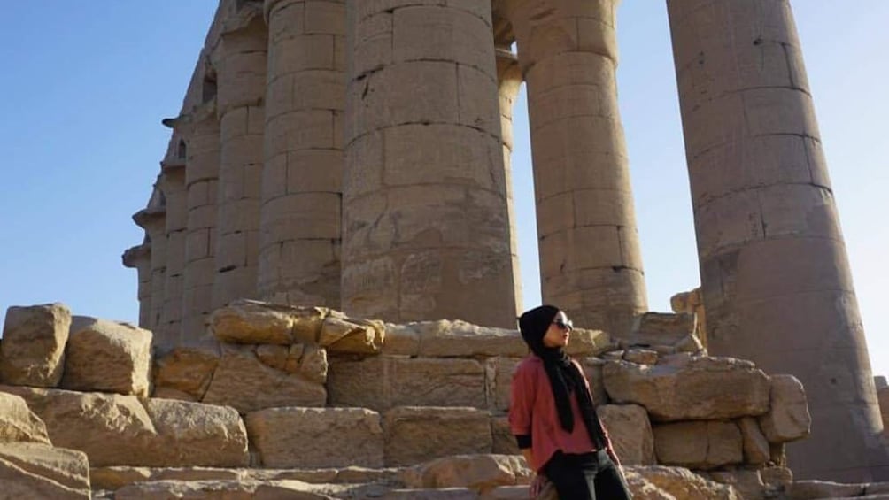 Tourist leans against stones near ancient Egyptian columns