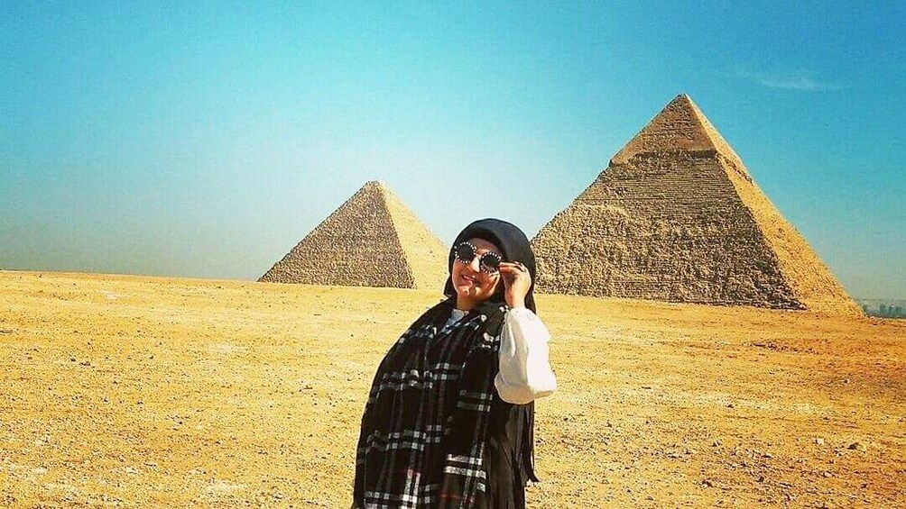 Woman with sunglasses poses in front of Pyramids of Giza