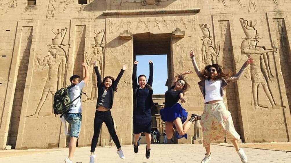 Tourists jump in front of Temple of Horus at Edfu