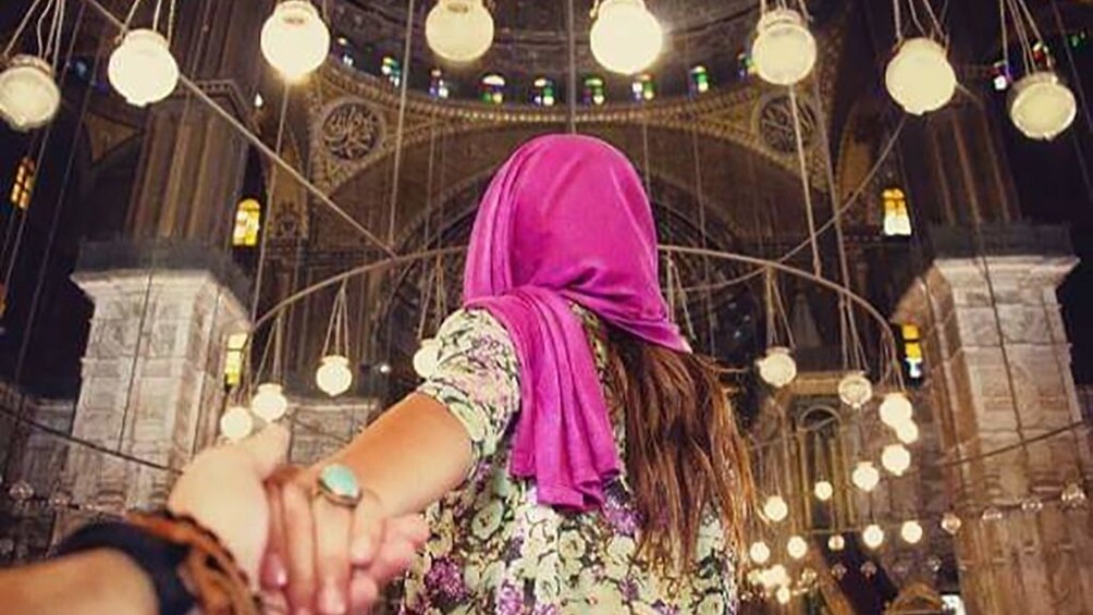 Woman with pink headscarf leads partner into Mosque of Muhammad Ali in Cairo, Egypt