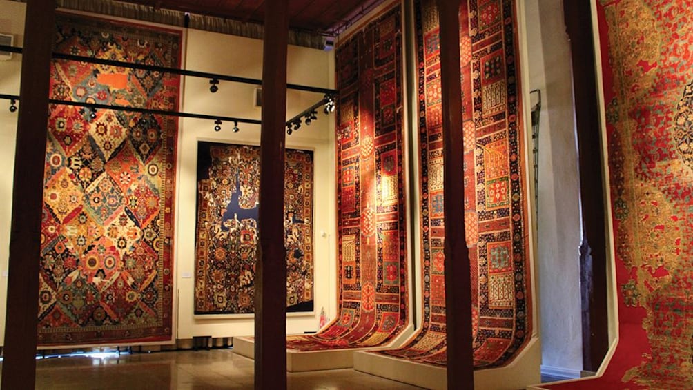 Large, colorful rugs hang from walls at Istanbul bazaar