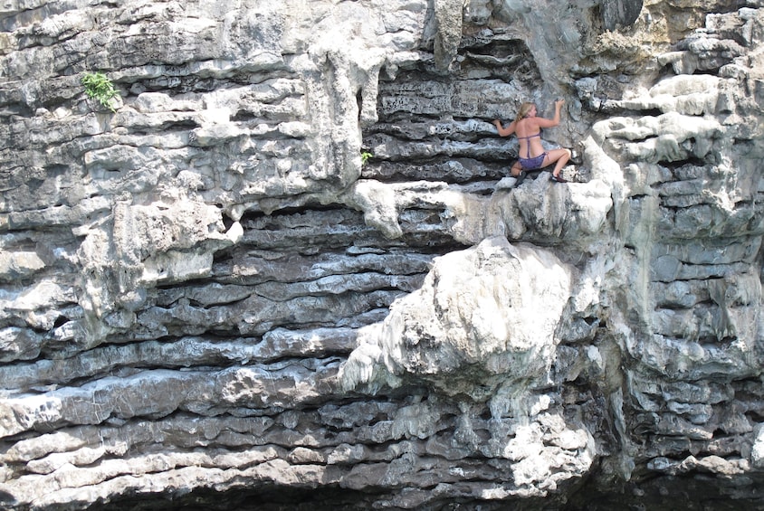 Woman climbs stone wall in Thailand