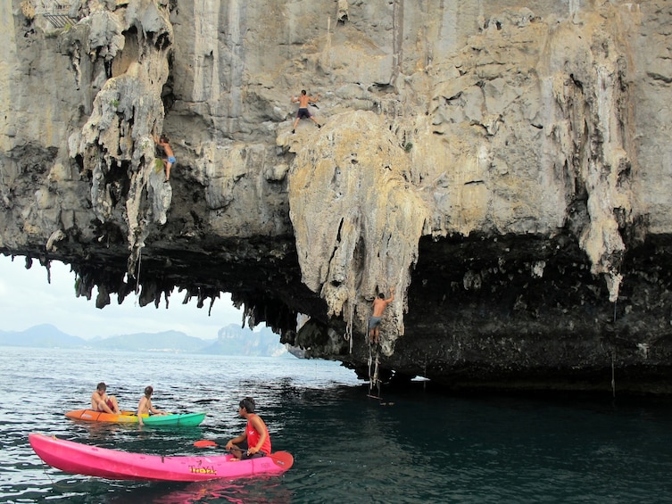 Tourists in small colorful boats under low hanging cave in Thailand